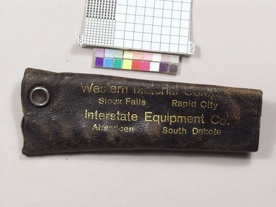 Hearst Museum object 2 of 2 titled Bottle opener, accession number 2-68926a,b, described as Pocket corkscrew, advertising souvenir. a) Corkscrew/caplifter combination; nickel plated flat steel shank, hole at one end crown caplifter at other; folding wire helical worm held in place with rivet, 7.4 cm long; b) leather case for above with snap, "Western Industrial Company Sioux Falls Rapid City", printed on case; 8.3 cm long