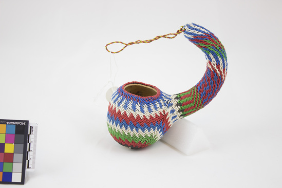 Hearst Museum object 3 of 4 titled Beer dipper, accession number 5-15352, described as Beer dipper; calabash covered with woven red, white, green, blue, and black telephone wire in a geometric design. Used to serve portions of beer. For tourist trade, domestic use-- sell or trade. Artisan: Simon Mungai.