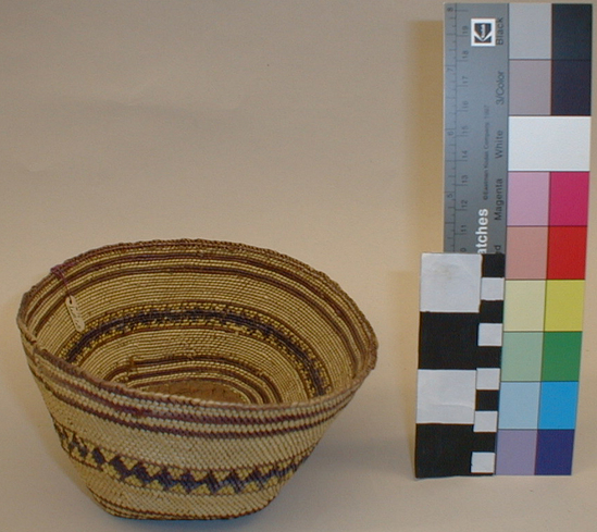 Hearst Museum object titled Basket, accession number 2-68486, described as Rounded rectangular shape with flat base, white grass overlay overall, narrow purple stripes on each side of a center band of dark blue diamonds.