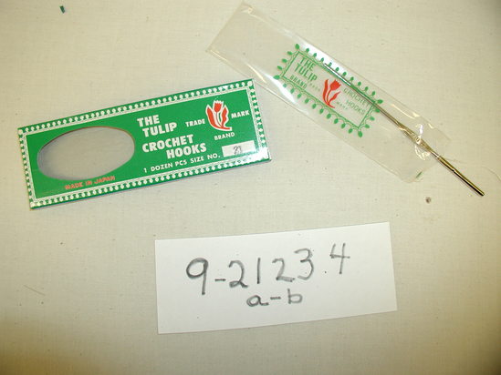 Hearst Museum object titled Crochet hook, accession number 9-21234a-c, described as Crochet hook in original packaging. One steel crochet hook (b) with cover.(Box made to contain one dozen.) Plastic cover (c) with “Red Tulip” brand trade mark. Blue and green box (a). 13.5cmx5cmx1cm.