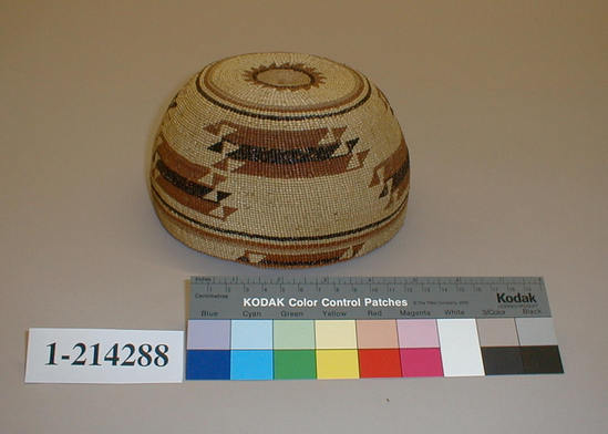 Hearst Museum object titled Basketry cap, accession number 1-214288, described as Twined basketry cap.  Design:  red and black on light ground; a sunburst design appears on top of cap.  Mostly plain-twined.