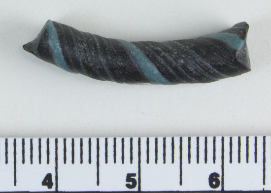 Hearst Museum object 6 of 6 titled Bracelet fragment, accession number 9-8049, described as Glass bracelet frag.; opaque black, twisted, curved rod w/ blue spiral; 27 x 7 mm.