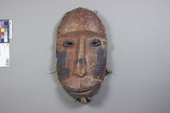 Hearst Museum object titled Mask, accession number 5-6266, described as Mask; wood; ovoid; incised indigo vertical lines on cheeks; indigo eyes and mouth; tuft of animal hair on chin. Height  28.5 cm. Width 16 cm.