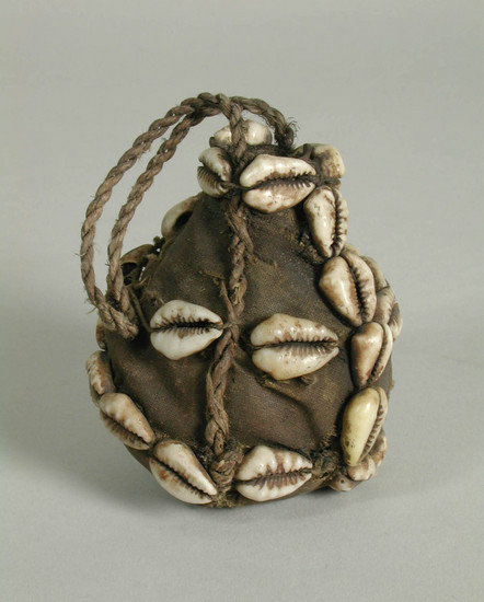 Hearst Museum object titled Charm, accession number 5-10188, described as charm;  gourd pear-shaped container;  covered with cloth;  bound with string and strung cowrie shells;  string handle;  contains seeds?;  H. 7.5 cm.