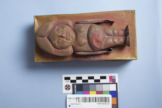 Hearst Museum object titled Box, accession number TEMP 2018.371.1, described as metal box with figure lying flat on top