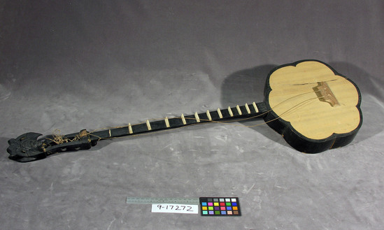 Hearst Museum object titled Musical instrument, accession number 9-17272, described as String musical instrument. Resembles banjo, wooden, neck & back, side, border of body are painted black; fingerboard is formed by bone triangular pieces; scroll is broken off; cracked soundbox; 3 pegs also broken from neck; twine-like veg. cord for strings. Nut has butterfly