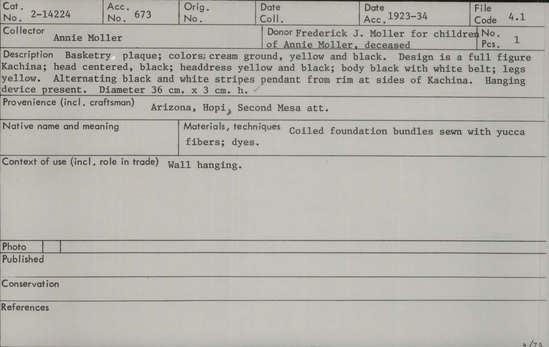 Documentation associated with Hearst Museum object titled Plaque, accession number 2-14224, described as Colors: cream ground, yellow and black.  Design is a full figure Kachina; head centered, black; headdress yellow and black; body black with white belt; legs yellow.  Alternating black and white stripes pendant from rim at sides of Kachina.  Hanging device present. Coiled grass bundle foundation sewn with split yucca fibers; dye.