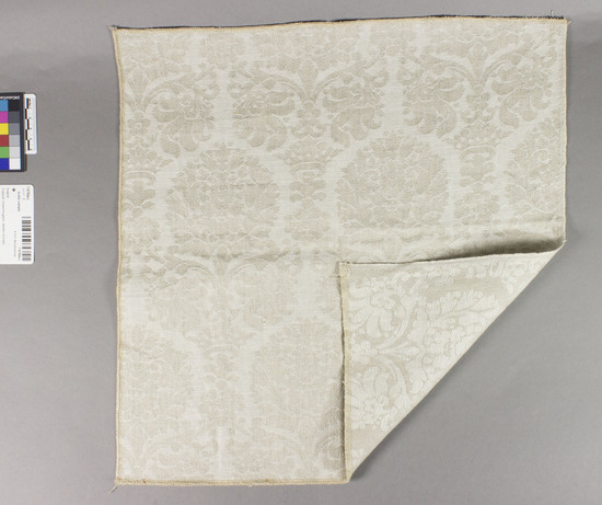 Hearst Museum object titled Textile sample, accession number 7-6784a-c, described as Damask Samples, Heavy linen, Damask weave,  a-brown &blue, b - gold&gray, c-beige&white, samples of heavy linen damask in baroque floral and crown motif. all edges overcast.  Jack Lenor Larsen, Inc.