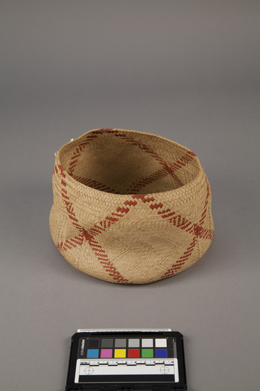 Hearst Museum object titled Fiber basket, accession number 11-42783, described as Basket, coconut leaf, plaited, diagonal red stripe on brown field. 18.0 cm diameter.