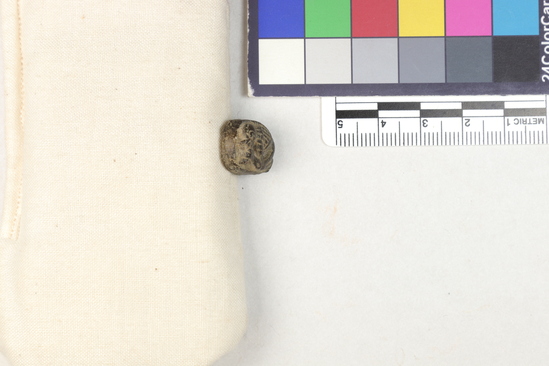 Hearst Museum object titled Amulet, accession number 5-13969, described as Amulet: carving of a seated baboon on front, holding something to its mouth. Inscription on back. Brownish color.