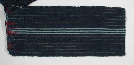 Hearst Museum object titled Textile fragment, accession number 5-11085, described as Textile sample (section of narrow band weaving): Navy ground with three central pale blue stripes & pale blue lines every .6 cm. Faint pale blue lines at bottom weft. Maroon threads woven into top.