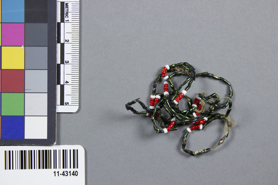 Hearst Museum object titled Necklace, accession number 11-43140, described as Necklace. Iridescent green beetle legs combined with white and red glass seed beads strung on cotton thread; fragile. length - 60.0 cm., approx.