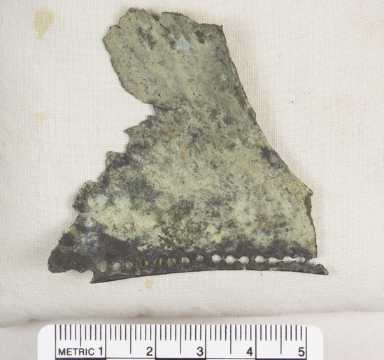 Hearst Museum object 38 of 45 titled Greaves, accession number 8-109, described as Bronze greave and 9 fragments small holes all around edge; serpent and scroll design raised and repousee; greave 41.9 cm long