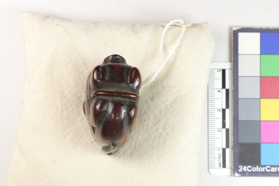 Hearst Museum object titled Netsuke, accession number 9-18876, described as Netsuke; abstract animal (dog ?) with tail, crouched over ball (?), sitting on haunches; smooth outline; signature not visible; H 3.9 cm X L 4.2 cm X W 2.2 cm