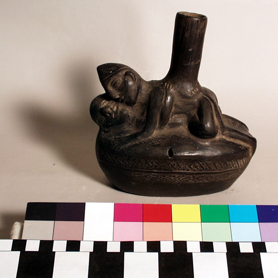 Hearst Museum object 2 of 2 titled Vessel, accession number 16-7523, described as Black-ware vessel; oblong body with pressed design, man and woman engaged in coitus lying on top straight cylindrical spout.