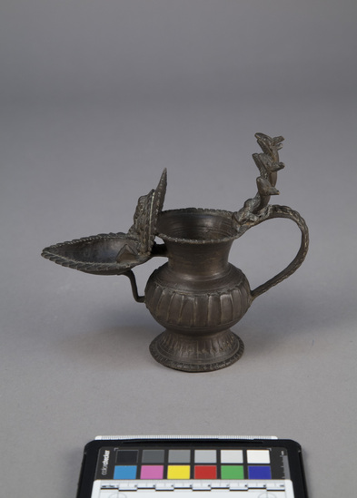 Hearst Museum object titled Oil lamp, accession number 9-9567, described as oil lamp; vessel (reservoir) with handle surmounted by 5 cobra heads supported by a god; heart-shaped oil well with fan-shaped vertical ornament with Ganesh in relief; ritual use; Ganesh is elephant-headed god, son of Shiva and Parvati