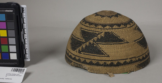 Hearst Museum object 2 of 2 titled Cap, accession number 1-9312, described as Woman's basket hat, black and white. Dirty from use. Plain twined except start and design area dividers. Almost completely overlain. Both 1 and 2 face overlay. White grass and maidenhair fern.  Geometric design.