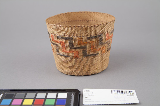 Hearst Museum object 2 of 3 titled Basket, accession number 2-63871, described as Cylindrical basket in plain twined spruce root with central design band of frets in brown and orange false embroidery; diagonal twined design bands on lower third of basket. Traditional shape. Dyes.