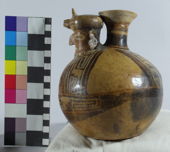 Hearst Museum object 4 of 13 titled Bottle, accession number 16-12115, described as Pottery bottle with flaring spout; effigy of a man with a turban with small spout in front; red and buff slip and resist painted designs; height: 19 cm. Has been waxed. See over.