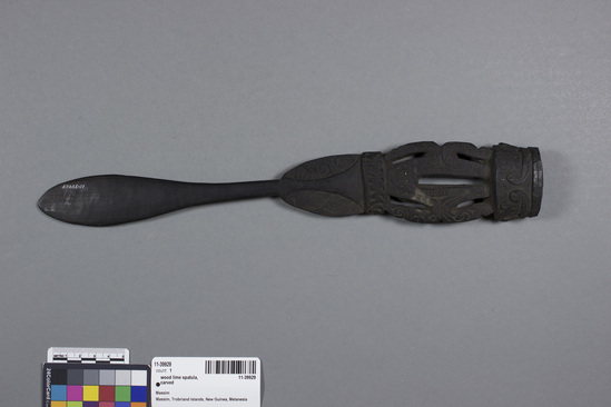 Hearst Museum object titled Lime spatula, accession number 11-39929, described as Lime-spatula of black wood, ponderous flat handle carved in the form of a double squatting figures. 35.1 cm length