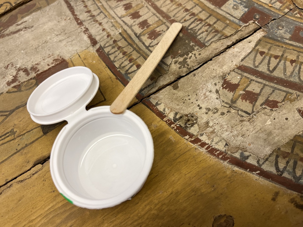 Hearst Museum object 164 of 167 titled Coffin, accession number 6-19912, described as Wooden anthropoid coffin. Inscription running down center of lid. Determined by Kea Johnston to probably be the outer coffin of Iwefaa (6-19928, 12-11039). According to Kea Johnston, "This coffin belonged to a man named Iwefaa, whose name is inserted in the middle of the spells written in the two columns on the front. This coffin is likely the outer coffin for PAHMA 6-19928 based on the similarity of the owner's name, unusual costume, and the paleography of the inscription. Both coffins were purchased on the antiquities market by George Reisner for Phoebe A Hearst. However, stylistically, they are very similar to a set of coffins known to have come from the site of Akhmim, which was excavated in the 1880s by Gaston Maspero, and which has heavily looted for the antiquities market during this decade." "The pectoral vignette between the text and the collar shows the deceased standing before squatting baboon and is the source of our logo. The hieroglyph for 'sky' is above their heads, and the side borders are formed by a pyramid and the symbol for the West.