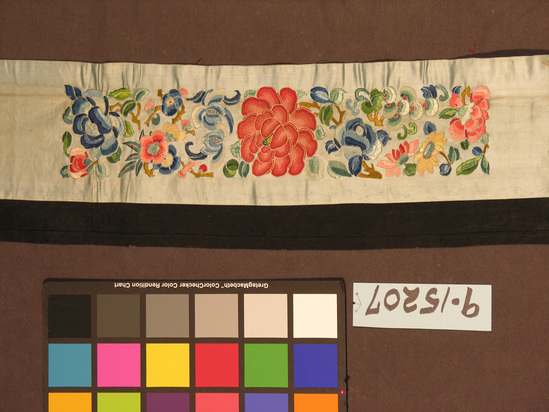 Hearst Museum object titled Textile strip, accession number 9-15207, described as Strip. 4.1. Silk. Satin, embroidered in satin stitch, outline, chain, Peking knot. Bias bound edges. Blue ground, varicolored embroidery. Floral motives. Same as #284. 7 inches by 37 inches.