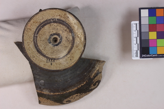 Hearst Museum object titled Kylix fragments, accession number 8-2301, described as Decadent Red-figure kylix (drinking cup); interior: Attic helmed head of Athena facing left; exterior: (Vitruvian?) scroll around body; below base: concentric dark circles around center; repaired from fragments, almost all of the missing.