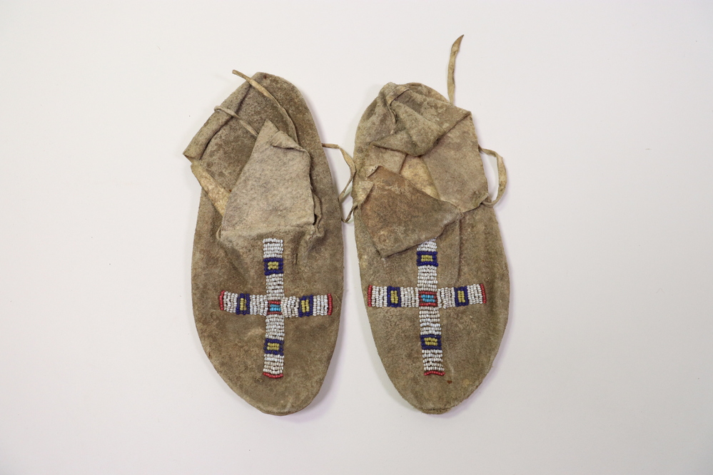 Hearst Museum object titled Moccasins, accession number 2-58338a,b, described as Pair of child's moccasins; buckskin; bead right-angle cross in white, red, blue and yellow on front of uppers. Glass trade beads.