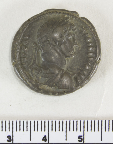 Hearst Museum object 5 of 6 titled Coin: billon tetradrachm, accession number 6-22597, described as obverse: head of Hadrian right, laureate, wearing cloak and cuirass reverse: Sarapis seated left