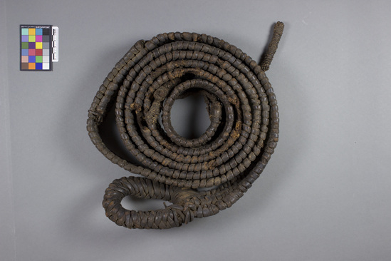 Hearst Museum object titled Leather rope, accession number 5-13397, described as Be-et., Kenya, Gob Ore, Rendille. Summer, 1977. 5-13397, acc no. 3332. Orig. No. 60. File code: 1.4 Collector: Jean Colvin. Donor: Jean Colvin. Materials, techniques: 4 sections plaited signal fibers over which is camel leather skin is dried & softened in water and plaited wet- several damaged sections of both leather and sisal. Context of use: Made and used by women to hold main frame put on camel for loads when moving. They use sticks from house as basic frame on to which other items are tied. Strap goes around camel's chest and tied in back to rope. Description: Strap- leather strips wound around 4 rows of plaited sisal fibers- The end with 4 tassels of sisal- other end loop of wound leather strips. L=340 cm. W=6 cm. References: for additional information see field sheets in acc. env.