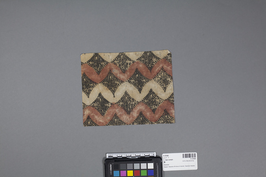 Hearst Museum object 2 of 3 titled Kapa (bark cloth), accession number 11-37049, described as Tapa cloth sample, with design of wavy white and red bands with black diamond filler.  Red bands painted with red vegetable dye; black designs achieved by stamping with charcoal dye.  This "kapa" made from thin "wauke" (Brigham "waoke" p.210) or paper mulberry, Broussonetia papyrifera (pp.119-121).  Reddish color from "noni" (morinda citrifolia) root. (fide Barbara (Kenani) Burns, 3 Aug. 1983).