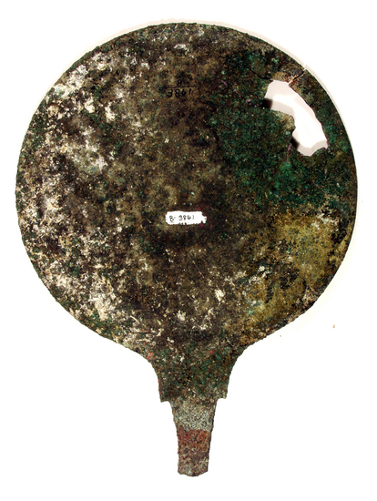 Hearst Museum object 7 of 9 titled Stemmed mirror, accession number 8-3861, described as Bronze mirror, stemmed, raised lip, Diameter 15 cm. Engraved with a winged Minerva (Greek: Athena) to left with sword and shield, over lotus flowers. A fairly large, irregular fragment is missing from the disc.