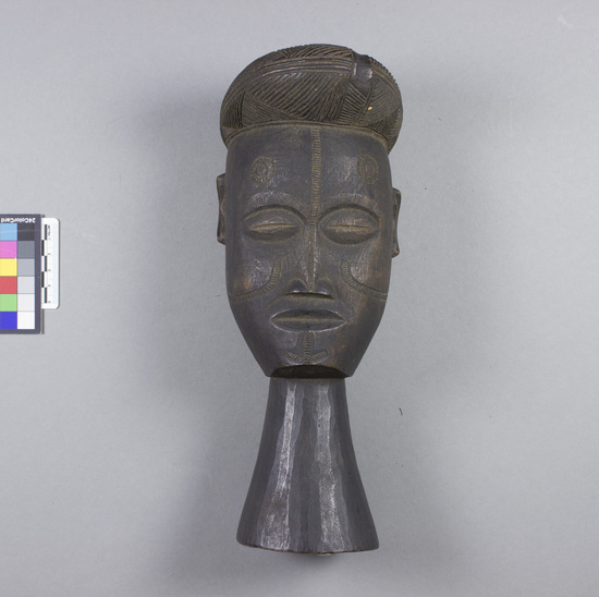 Hearst Museum object titled Head, accession number 5-6339, described as Head; wood; long neck as base; protuding head or hair-do decorated with incising; face incised with circular patterns on forehead and linear hatched patterns on nose, cheeks and chin; head slightly bollowed in back.