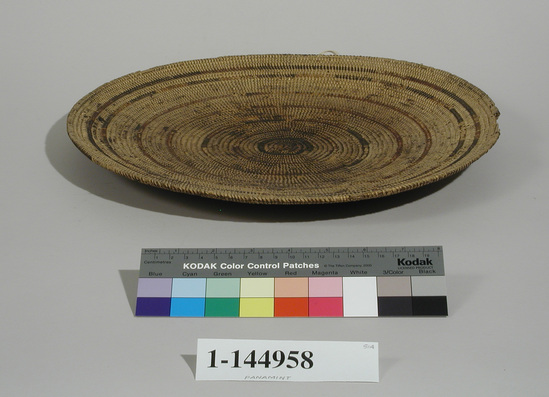 Hearst Museum object titled Winnowing tray, accession number 1-144958, described as Shallow, circular, coiled tray. Concentric circle design in red and black. Old and use-worn.