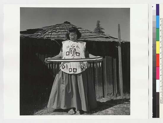 Hearst Museum object titled Black-and-white negative, accession number 15-20235, described as Essie Parrish holding costume; men's white jacket with decorations and belt (long pendants)