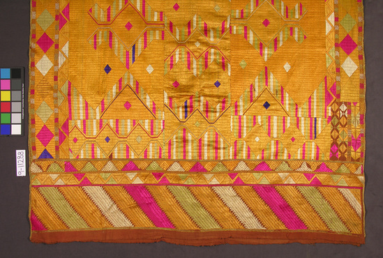 Hearst Museum object titled Shawl, accession number 9-11288, described as Shawl or head cover; rust colored cotton in three narrow widths sewn together and covered with silk embroidery (satin, cross, blanket and stem stitches) in gold, white, pale green, purple and pink geometric designs; length 250 cm, width 140 cm.