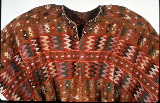 Hearst Museum object 2 of 3 titled Huipil, accession number 3-66, described as Woman’s shirt (huipil); 3-66 lower part white cotton plain weave; upper part brown cotton brocaded in brown, green, lavender, reds, greens and whites; neck bound and embroidered on black ribbon; approximately 1 m wide, 104 cm long Brown is the natural color of the variety of the cotton.