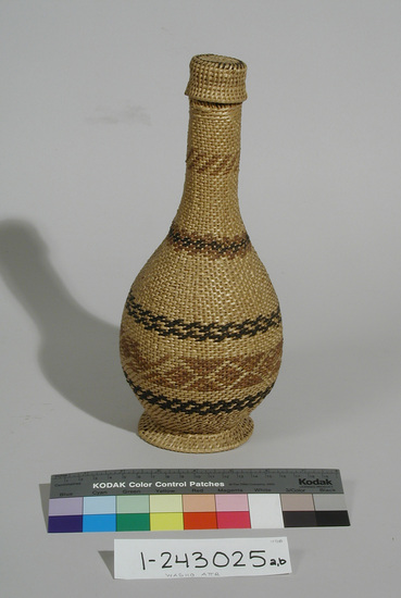 Hearst Museum object titled Bottle and cap, accession number 1-243025a,b, described as Basketry covered with top.  a) Twined basket tightly fitting over green glass bottle, bowl shaped body, narrow neck, split/unsplit willow shoots, 2 bands bracken fern root, one band winter peeled willow and bracken fern root, one band winter peeled willow one band diamond/pyramid designs of winter peeled willows, circular base of willow shoots.  b) Top.  Coiled willow shoots, one row bracken fern root.