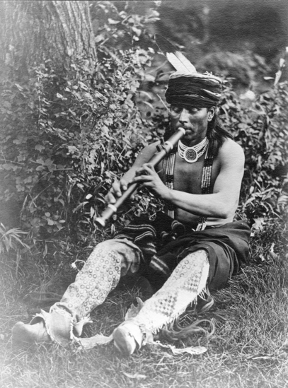 Hearst Museum object titled Photograph, accession number 13-96, described as Omaha man wearing traditional costume, playing flute.