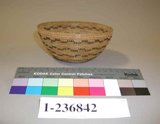 Hearst Museum object titled Basket, accession number 1-236842, described as Coiled. Flat bottomed conical shape. Design: horizontal rows of checked pattern in black. Remains of red wool yarn decoration near rim. Diagonal overstitching on rim. Grass bundle foundation, sewing strands of sedge and bracken fern roots.