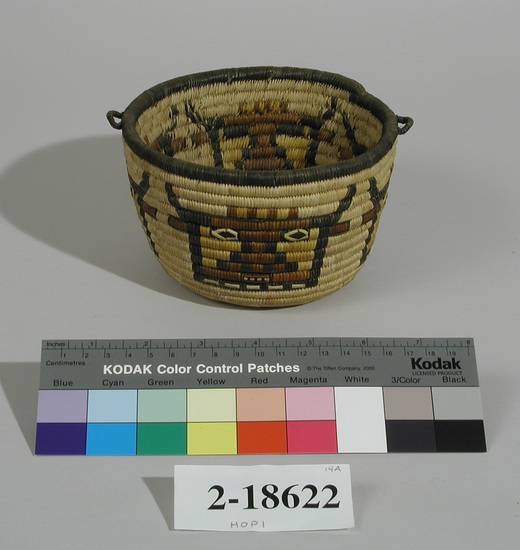 Hearst Museum object titled Basket, accession number 2-18622, described as Coiled, brown, yellow and black Kachina design; rim is black; handles on either end sewn into rim coil; flat bottom.