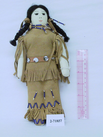 Hearst Museum object titled Doll, accession number 2-71857, described as Apache, cloth stuffed doll, with painted features and mohair hair in two braids. Buckskin blouse and skirt with self fringe. Decorated with blue tube beads, gold & clear beads and silver sequins. Buckskin boots, knife sheath, pouch and hair ties, both of which are beaded and decorated with silver sequins. Height 9.75 inches