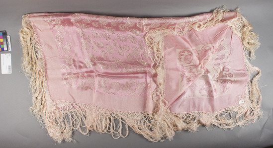 Hearst Museum object titled Kerchief, accession number 7-5125, described as Woman's silk kerchief (rizince-koprineno); worn as a decorative apron; pink with embroidered floral design; fringed; 31" square. Rizince-local dialect for kerchief; kaprineno- silk. Worn by young women over regular apron as part of festive costume; costume of older women in same area does not include this item, although otherwise similar. At one time these were imported from Istanbul or Solika via Debar. Still worn at time of collection, 1964. 7-5119-5128 comprise a complete costume.