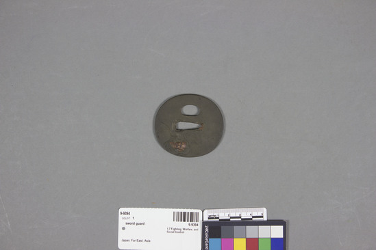Hearst Museum object titled Sword guard, accession number 9-9394, described as oval; iron; Zen monk on front; incense and fly whisk on back; copper inlay and engraving; 6.2 x 5.7 cm.