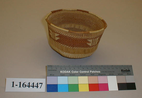 Hearst Museum object titled Treasure basket, accession number 1-164447, described as Twined basket with two bands of openwork. Tag "Klamath River Tribes att.". Per Ralph Shanks: Twined openwork basket, made for sale. Crossed warp starting knot. The warp material is probably hazel or willow. The basket has conifer root wefts. The overlay weft material is beargrass and red-dyed Woodwardia. Starting at the starting knot, there is one weft row of plain twining, followed by 0.25 inch of three strand twining, followed by plain twining to the edge of the base where there are two weft rows of three strand twining followed by plain twining for a 0.5 inch. Going up the sides of the basket there is a 0.5 inch of parallel warp openwork, followed by 1.5 inches of close work plain twining followed by ⅓ inch of parallel warp openwork. At the rim there are two weft rows of plain twining, a single strand of beargrass and a reinforcing rod wrapped with beargrass alternating with red-dyed Woodwardia. The main design is four sets of paired stacked triangles separated by two vertical lines. The basket has a rightward work direction, with an up to the right slant of weft twist. The overlay is single sided, with the design on the exterior. The workface is on the exterior. The basket is from Northwestern California.