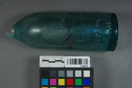 Hearst Museum object 2 of 2 titled Glass bottle fragment and stopper, accession number 1-249952, described as 3-part hinge mold aqua embossed soda bottle with maker's mark
