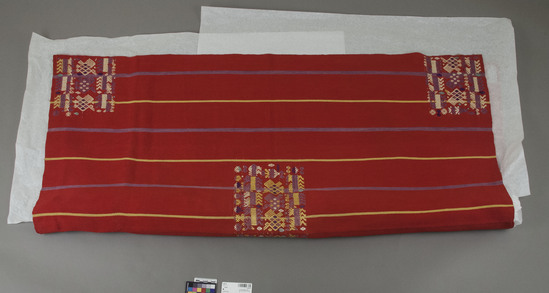 Hearst Museum object titled Shawl, accession number 3-28110, described as Woman’s ceremonial shawl.  Cotton, silk.  Plain weave, brocaded.  Red ground, magenta, yellow stripes, varicolored designs.  Animal, bird, floral, geometric motives.  See Fig. 105, Textiles of Highland Guatemala.  50 inches x 46 inches