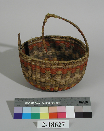 Hearst Museum object titled Basket, accession number 2-18627, described as Wicker, plain, with handle.  Colors, red, green, black, yellow, cream, brown.  Overall decoration; red bottom, alternating colors in sides.  Handle broken in two places, one of which was repaired before accession.  Rim finish is wrapped.