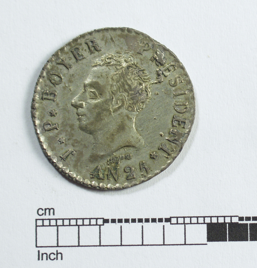 Hearst Museum object titled Coin: 50 centimes, accession number 3-23400, described as Coin, silver and copper Obverse: President Boyer facing left; “President J.P. Boyer” AN 25 Reverse: Two cannons with two spears, four guns with bayonets, and four flags mounted on them. A palm tree standing in the middle with the liberty cap perched on top. “Republique D’Haiti 50*C” Denomination: 50 centimes Weight: 5.00 g Content: Ag and Cu Mint Date: 1827 References: Craig 36