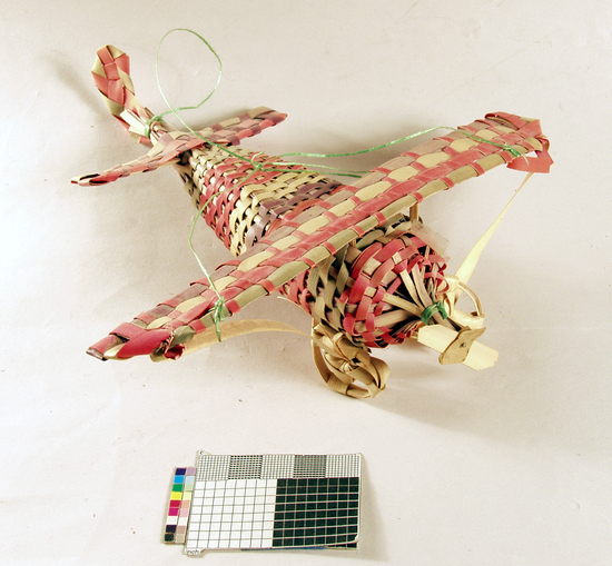 Hearst Museum object 4 of 4 titled Toy airplane, accession number 3-29240, described as Toy airplane, palm leaf in wickerweave; red, green and black; poor condition; L 20 cm.
